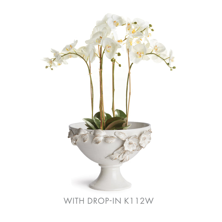 White floral pedestal bowl styled with a cream artificial orchid drop-in and green leaves at the base in Traditional style