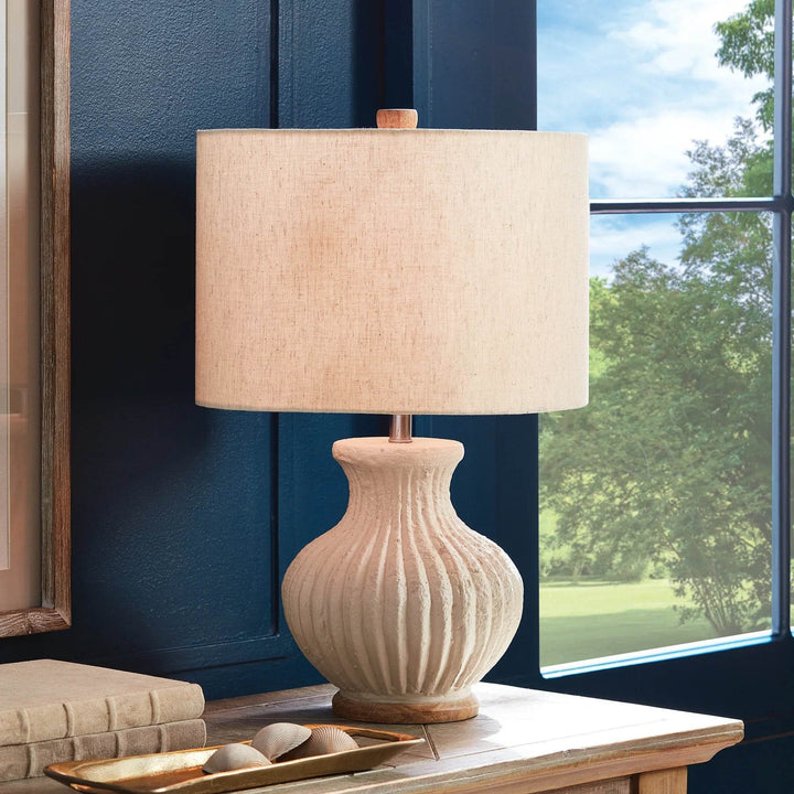 Wabi sabi table lamp placed beside window with soft daylight, showing linen shade and curved ribbed silhouette