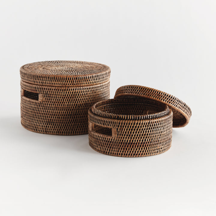 Warm brown round rattan boxes with one lid removed, showing the woven interior and graduated sizes on white, Traditional