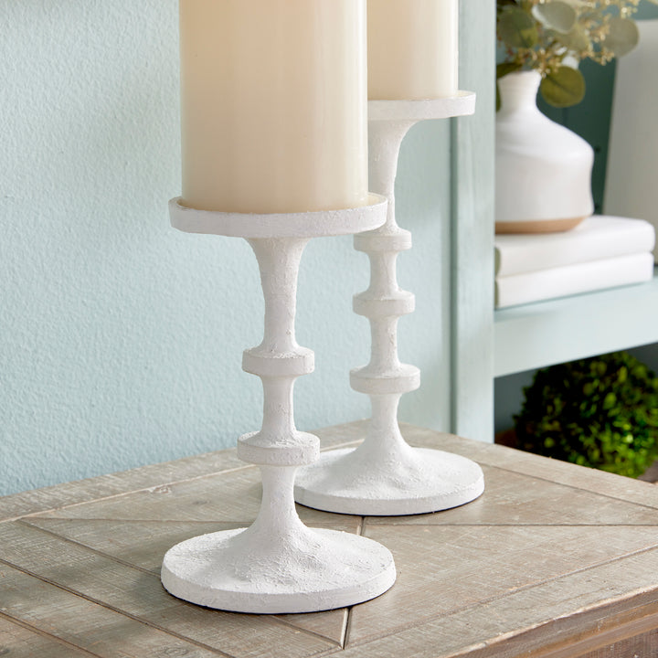 White aluminum candle holders with sculptural stacked silhouette and elevated pillar candle display – Transitional