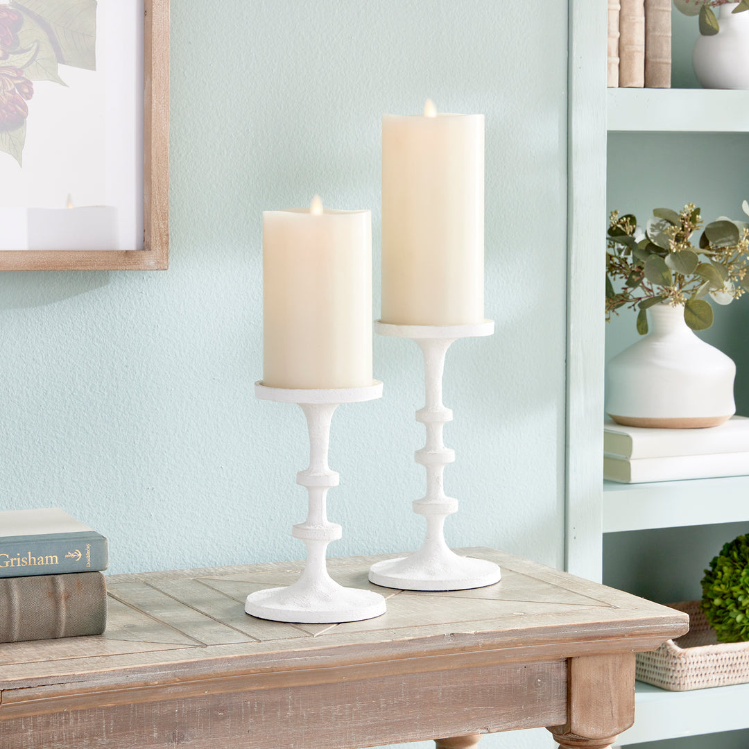 White aluminum pillar candle holders styled on a tabletop with layered neutral home decor – Transitional