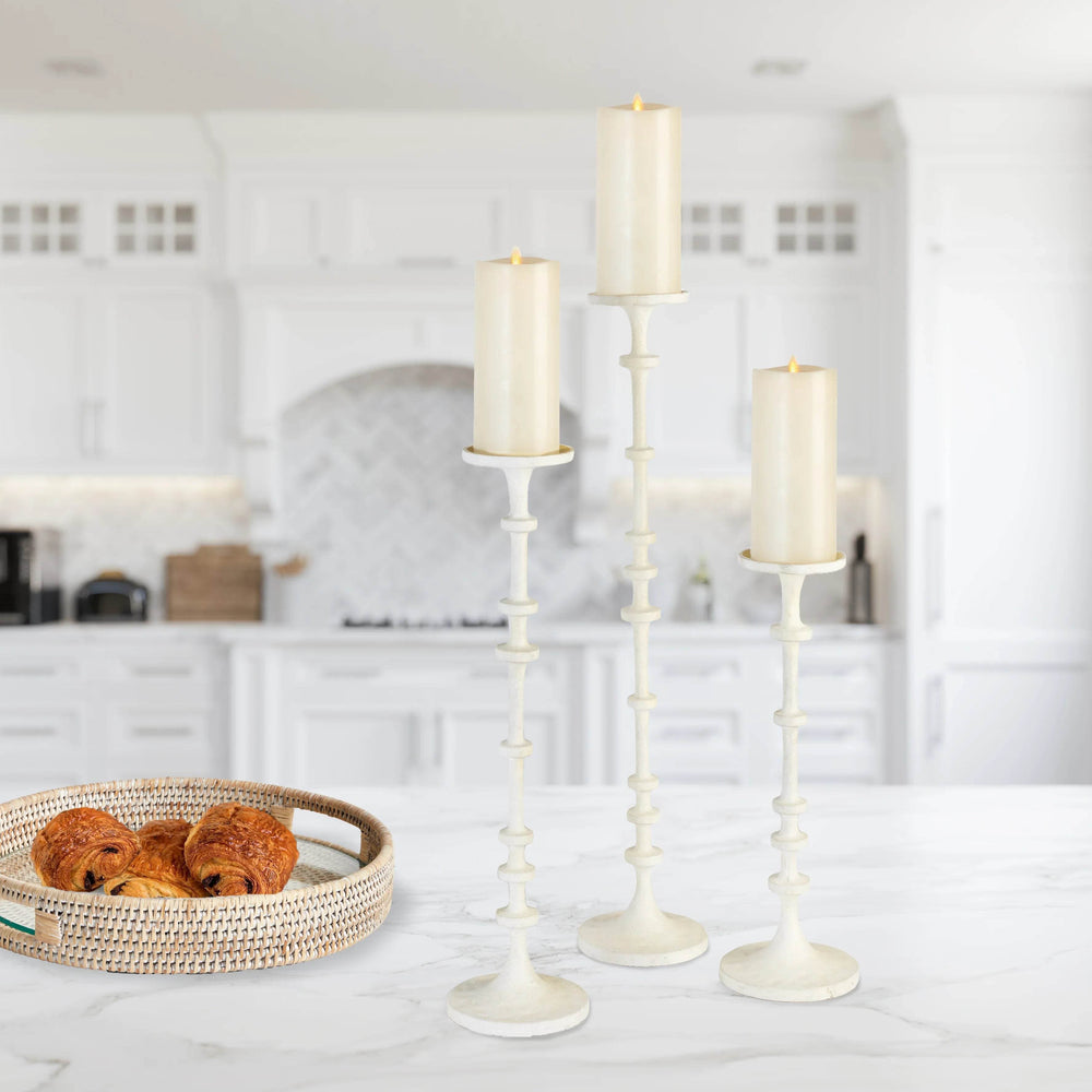Trio of tall white pillar candle stands styled on a kitchen island with LED candles, clean neutral surfaces and airy farmhouse look – Modern Farmhouse.