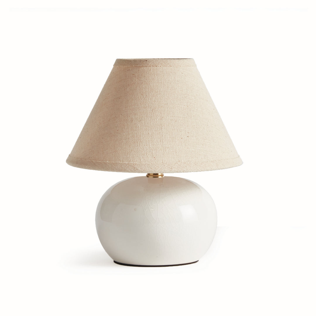 White ceramic mini table lamp with a rounded glazed base and tapered cream linen shade on plain white - Coastal Transitional