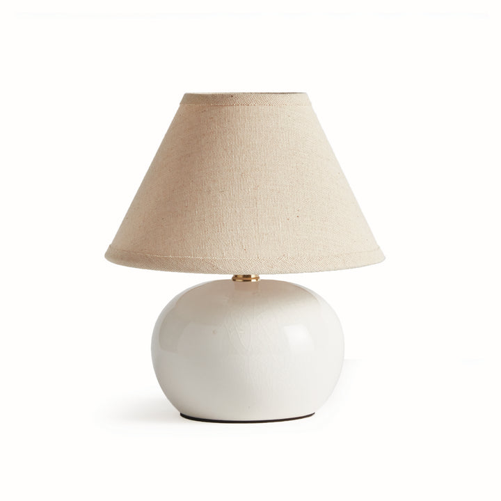 White ceramic mini table lamp with a rounded glazed base and tapered cream linen shade on plain white - Coastal Transitional