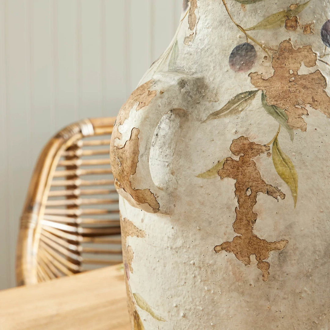 Close-up detail of one ceramic pot handle, showing hand-applied vine motif and aged flaked finish on white clay.
