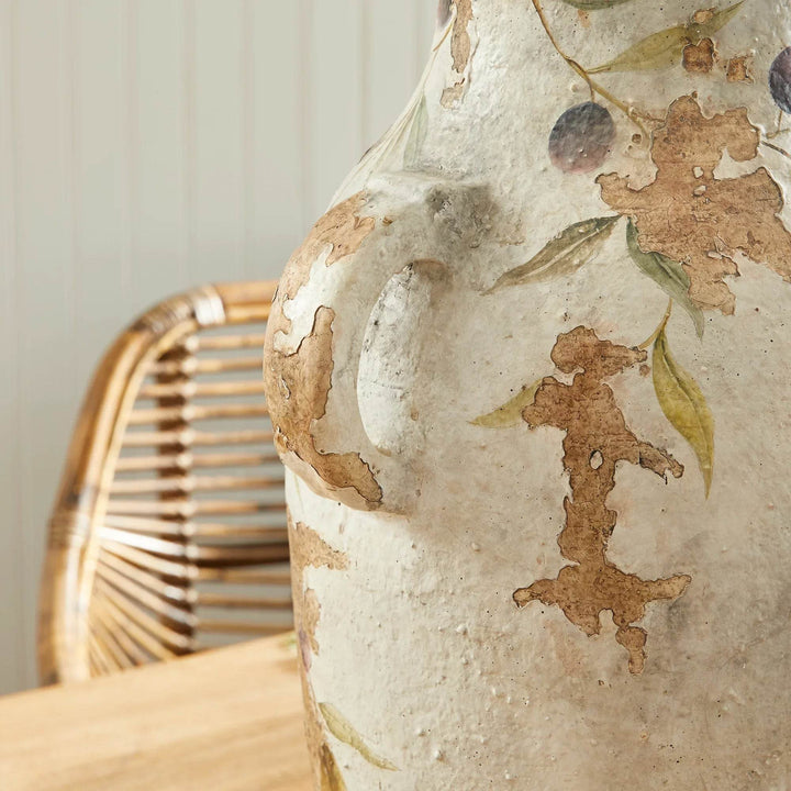 Close-up detail of one ceramic pot handle, showing hand-applied vine motif and aged flaked finish on white clay.
