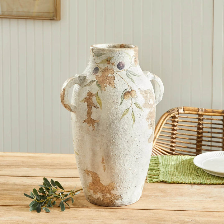 Large white ceramic pot with handles on natural wood table, styled in a cozy kitchen setting with green table runner.