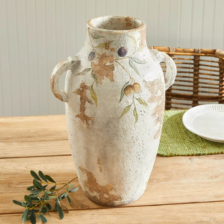 Full-size white ceramic urn with handles displayed in a casual dining setting, surrounded by rustic furniture and décor.