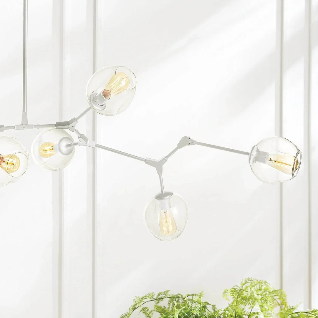 White chandelier branch close-up with adjustable joints and clear glass globes beside bright window, Mid-Century Modern style