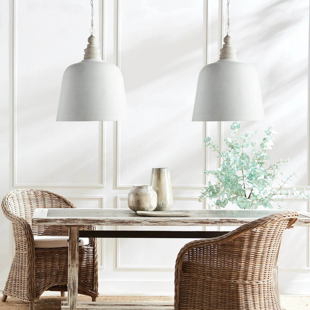 Two white dome pendants over a wood dining table, with woven chairs and greenery beside bright window, Modern Farmhouse style