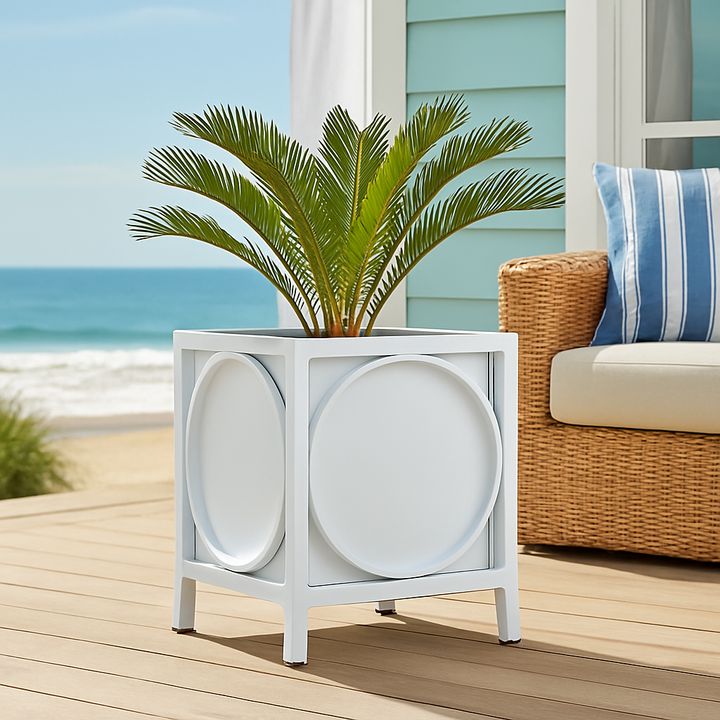 White metal planter with lush greenery styled on a coastal deck with natural wood and striped textiles.