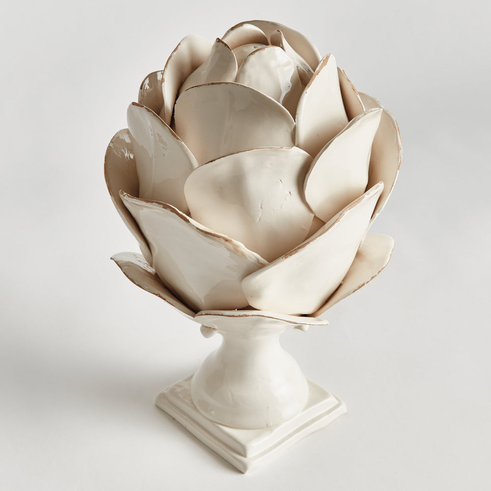 Angled view of a white ceramic petal finial showing layered petals, antiqued edges and its square pedestal base, Traditional