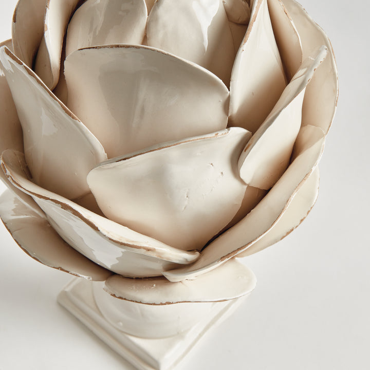Close view of layered white ceramic petals with softly antiqued edges on a sculptural decorative finial on white, Traditional