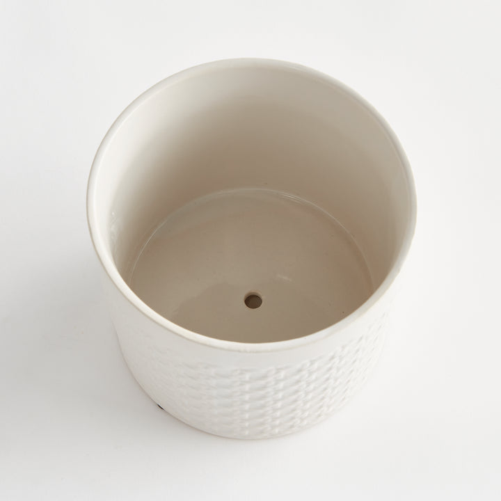 Top view into a white round ceramic planter, showing its smooth interior and central drainage hole against white, Traditional