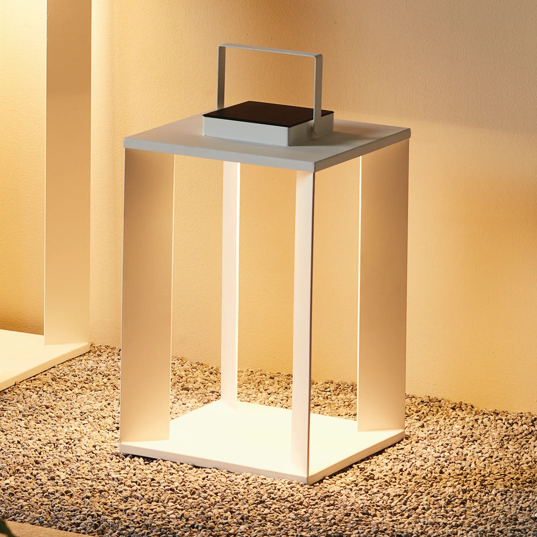 White solar LED lantern glowing on gravel surface, modern outdoor lighting accent with warm illumination for patio and entry styling