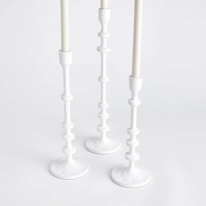 Three white taper candle holders shown together from an angled view, textured matte finish and sculptural column stems – Modern Farmhouse.