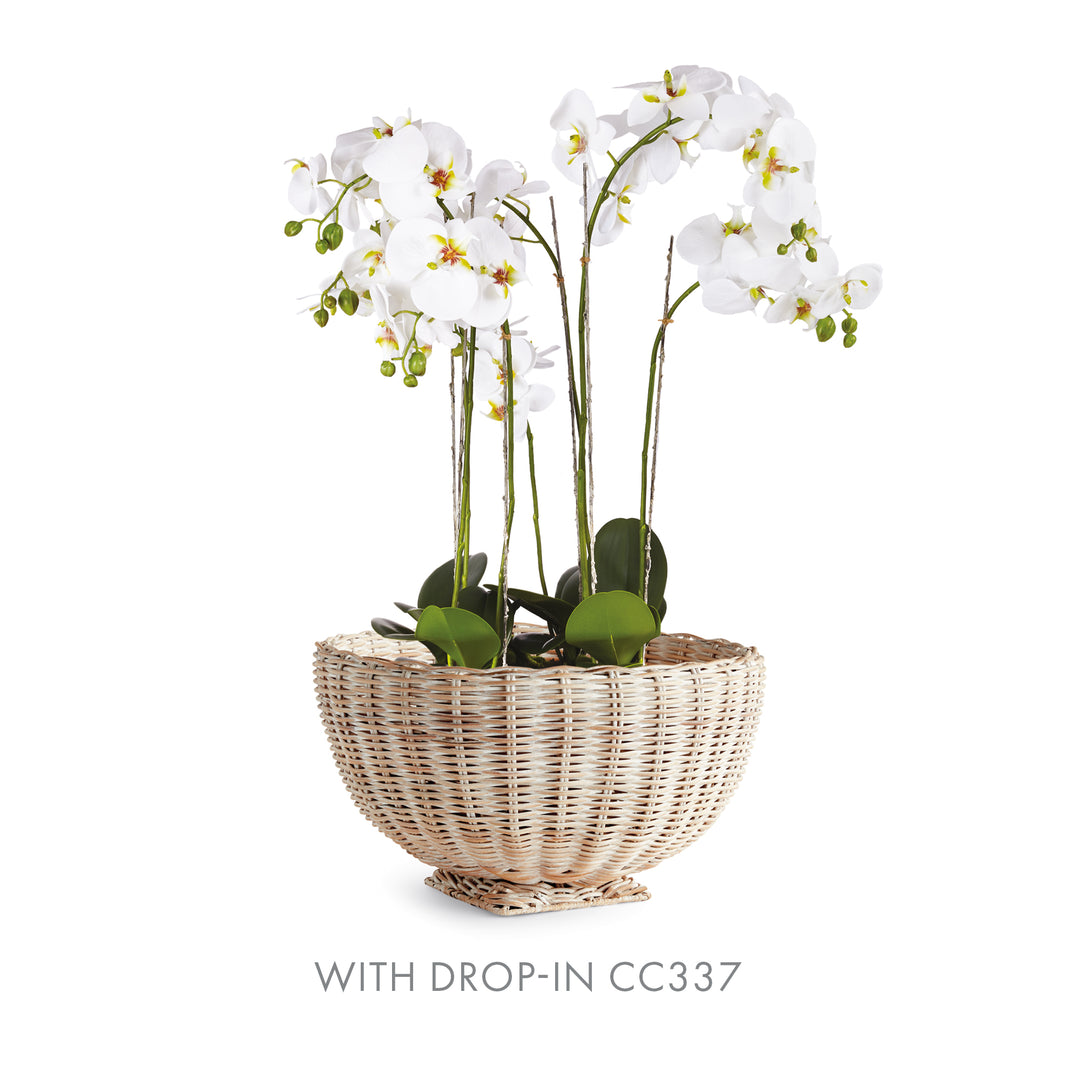 Whitewash rattan footed bowl styled with white orchid flowers and green foliage above its woven rim - Coastal Transitional