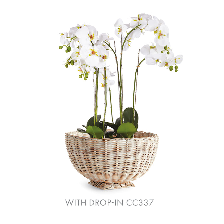 Whitewash rattan footed bowl styled with white orchid flowers and green foliage above its woven rim - Coastal Transitional