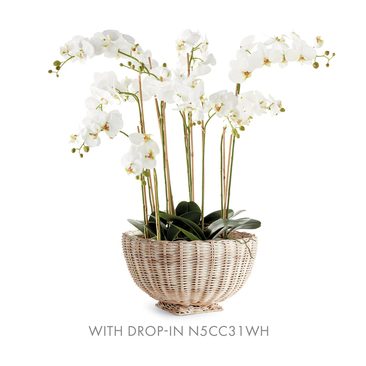 Whitewash rattan footed bowl holding tall white orchids with slim support stakes, shown on plain white - Coastal Transitional