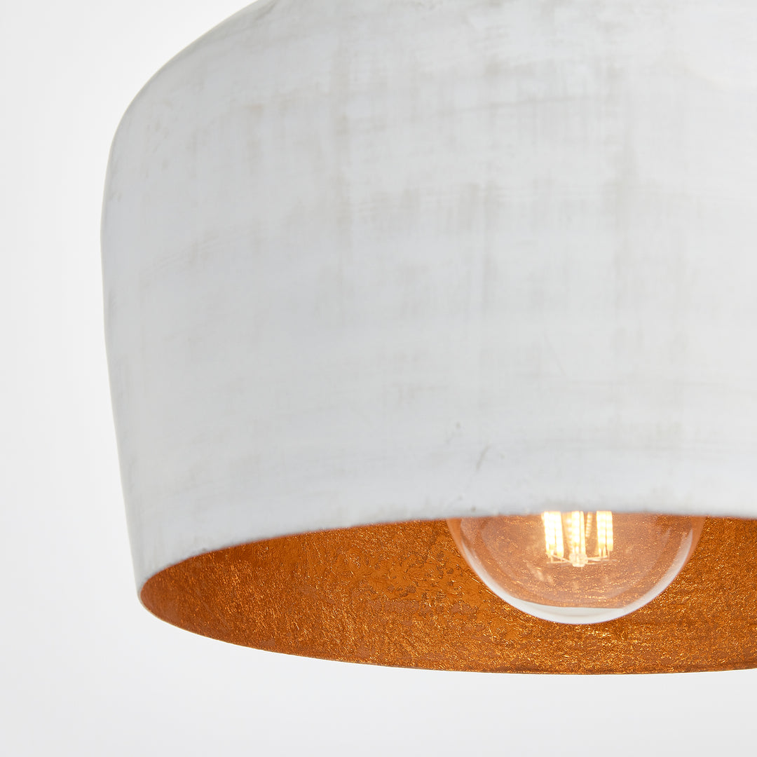 Whitewashed iron bell pendant shade viewed from below, showing a gold interior, pale rim and exposed bulb, Transitional style