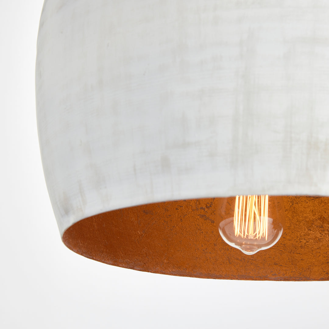 Whitewashed rounded dome pendant viewed from below, showing gold interior and exposed bulb behind the rim, Transitional style