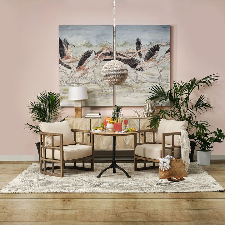 Wood beaded pendant light above a round dining table with upholstered chairs, plants and bird artwork on pink wall – Coastal