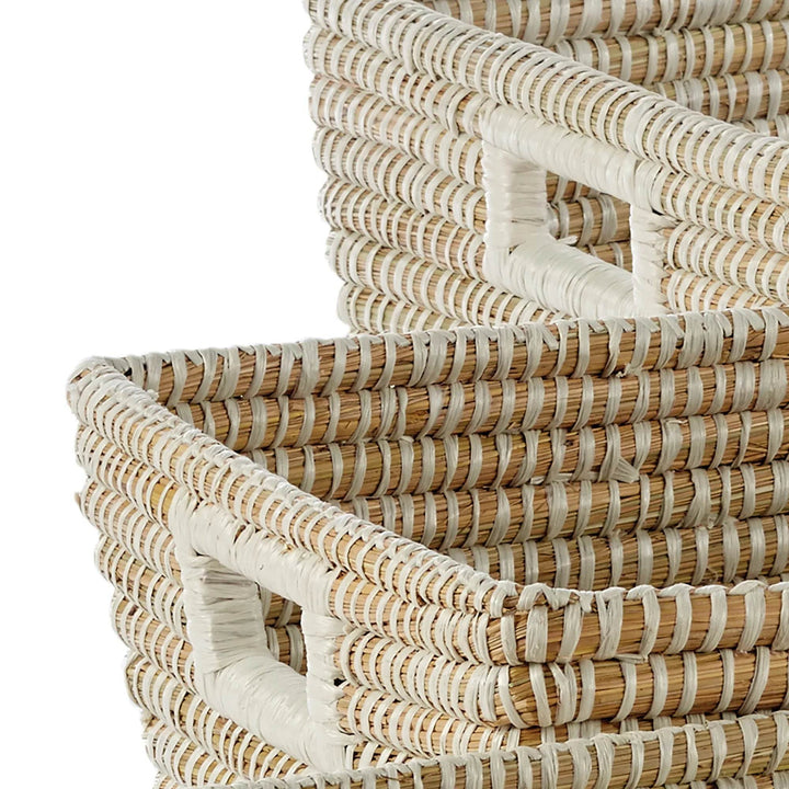 Detail shot of natural woven baskets with white wrapped handles, highlighting texture and artisanal craftsmanship.