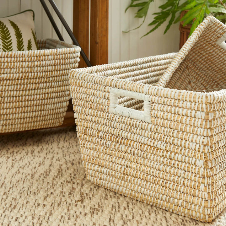 Close-up of handwoven storage baskets with white handles, ideal for storing blankets, pillows, or toys in modern homes.