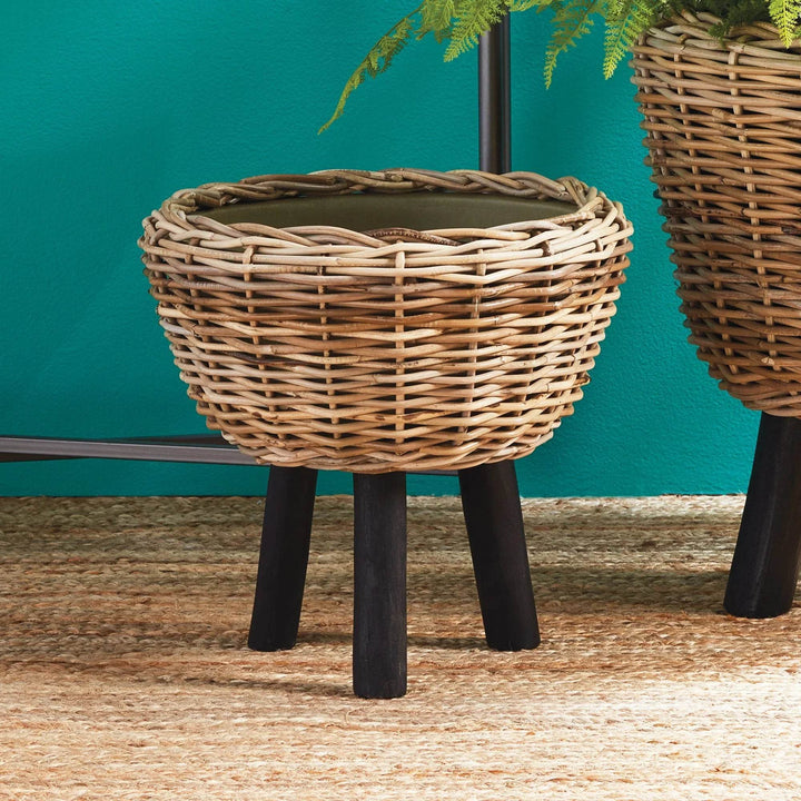 Elevated wicker planter on jute rug in front of teal wall, modern organic look
